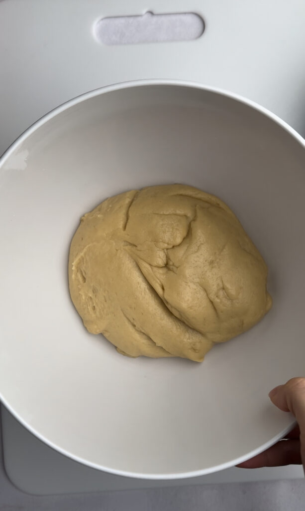 Kneaded dough in a white bowl.