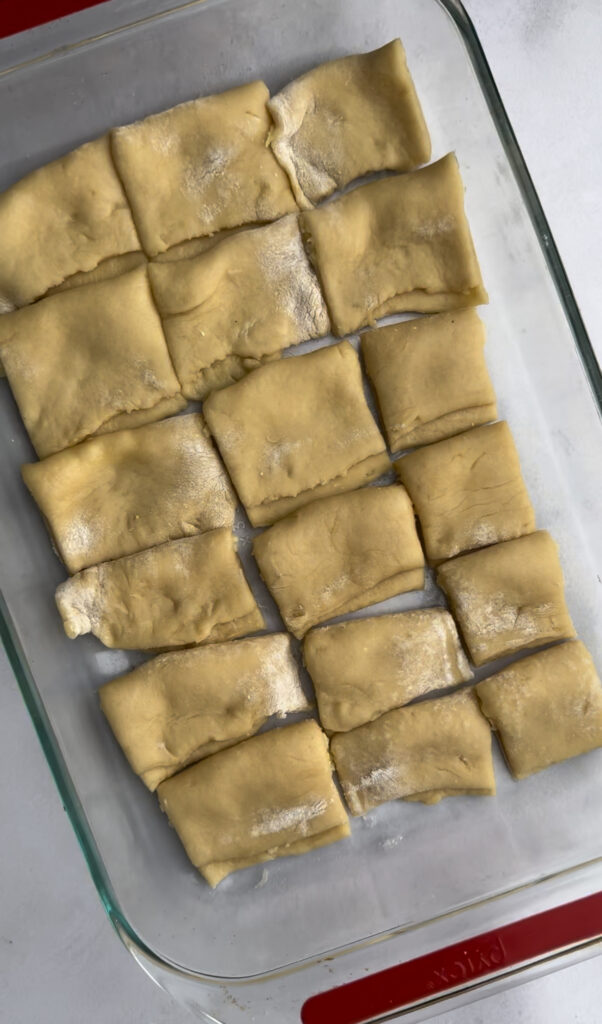 Dough logs are cut into squares and laid in a 9x13 pan.