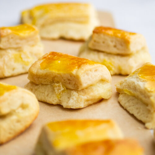 a bunch of cheese rolls on a piece of parchment against a gray background.