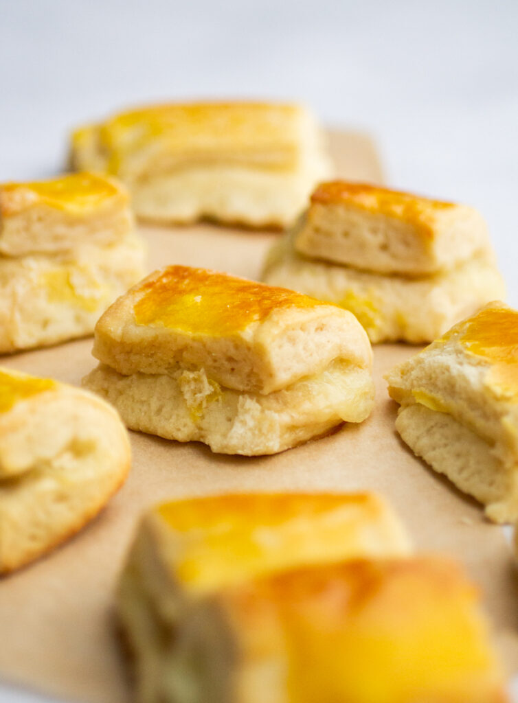 a bunch of cheese rolls on a piece of parchment against a gray background.
