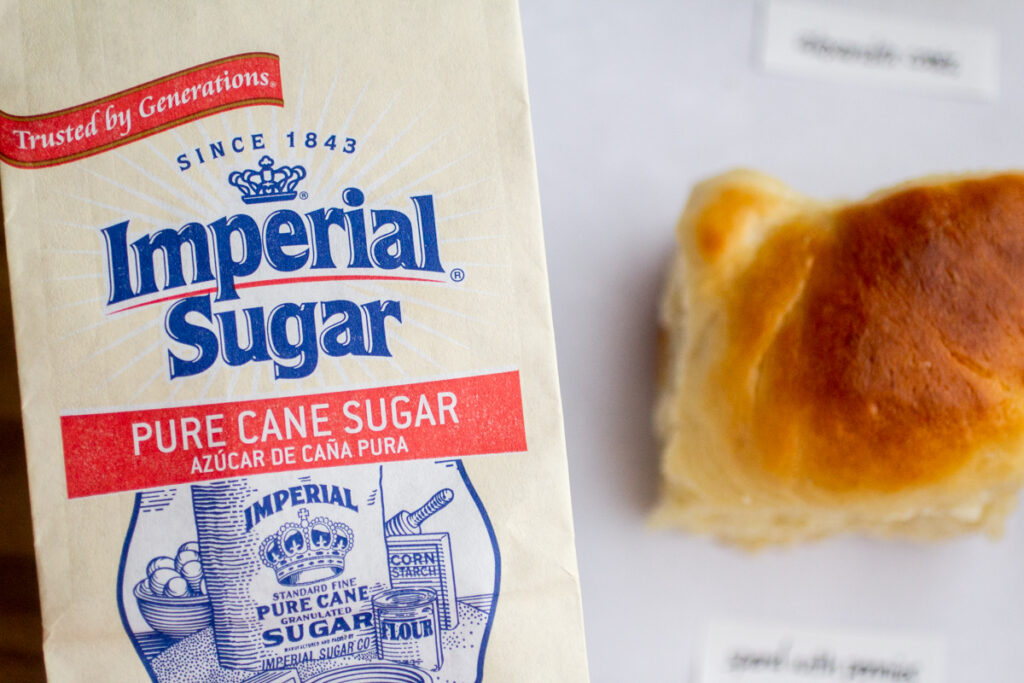 a bag of Imperial Sugar next to a dinner roll.