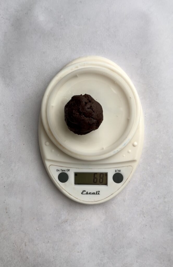 A ball of chocolate cookie dough on a scale.