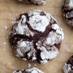 a thick chocolate crinkle cookie on a sheet of parchment paper.