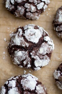 a thick chocolate crinkle cookie on a sheet of parchment paper.