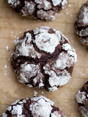 a thick chocolate crinkle cookie on a sheet of parchment paper.