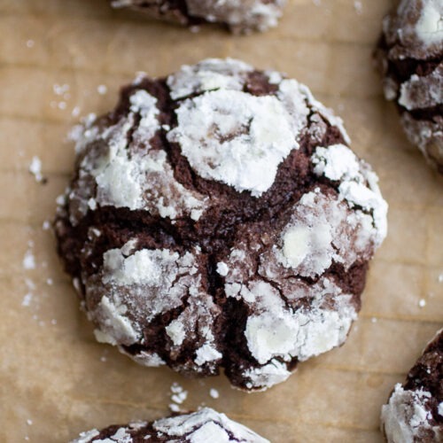 a thick chocolate crinkle cookie on a sheet of parchment paper.