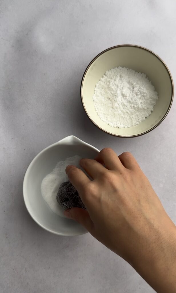 Rolling a ball of dough in granulated sugar.