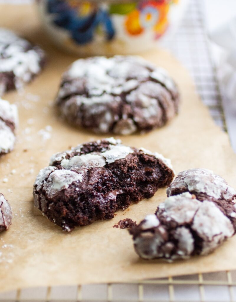 A chocolate crinkle cookie broken into two pieces to expose the gooey interior.