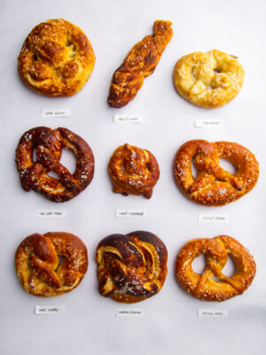 9 different soft pretzels on a gray background.