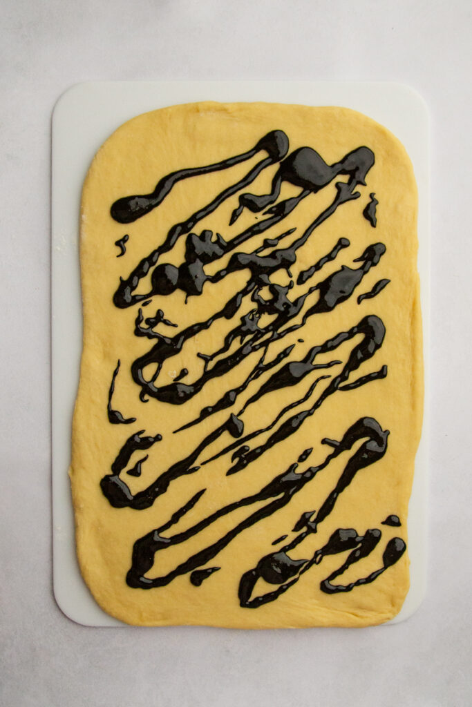 Rolled out dough with black sesame paste drizzled on top.