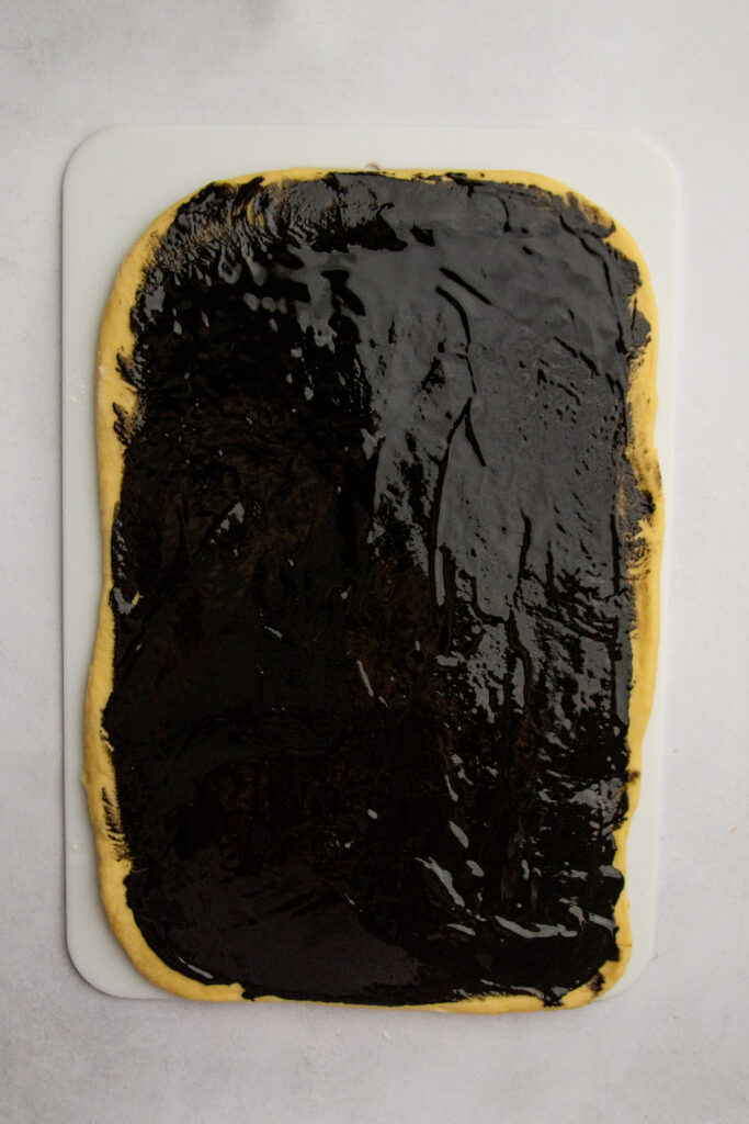 Rolled out dough with black sesame paste spread evenly over the top.