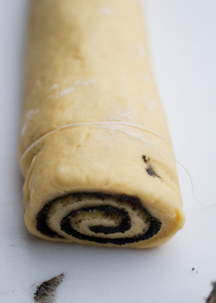 Black sesame roll cylinder with a piece of floss wrapped around it.