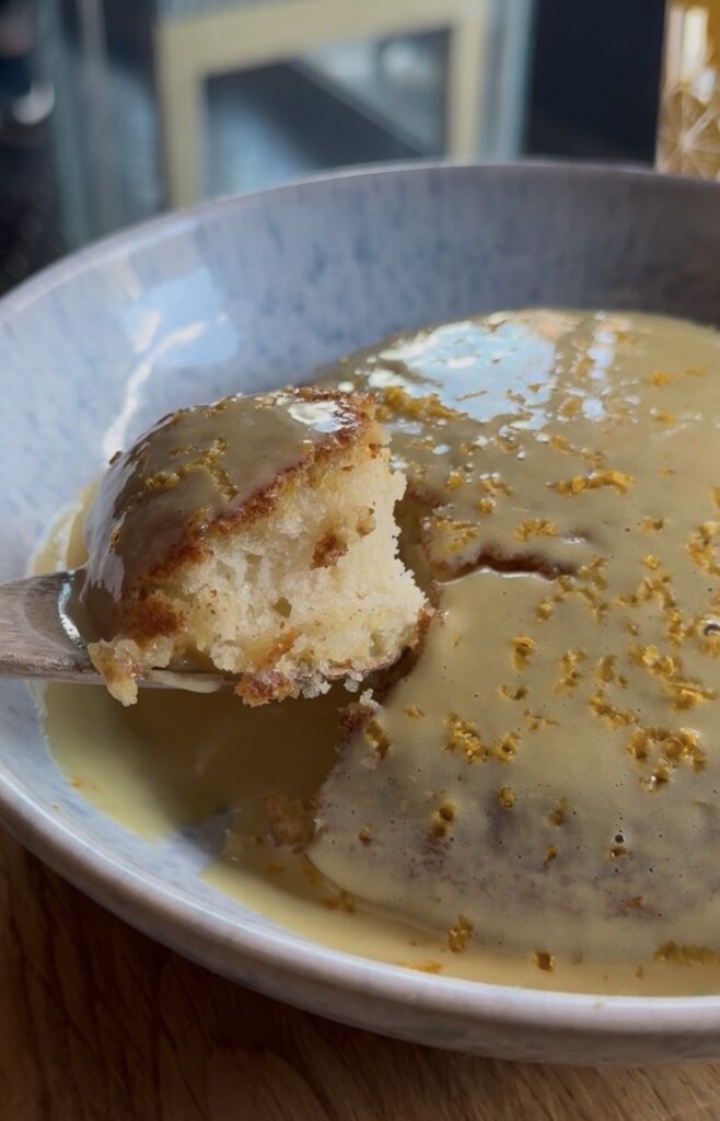 A bite out of a salted egg pancake held up on a fork to show the fluffy interior.