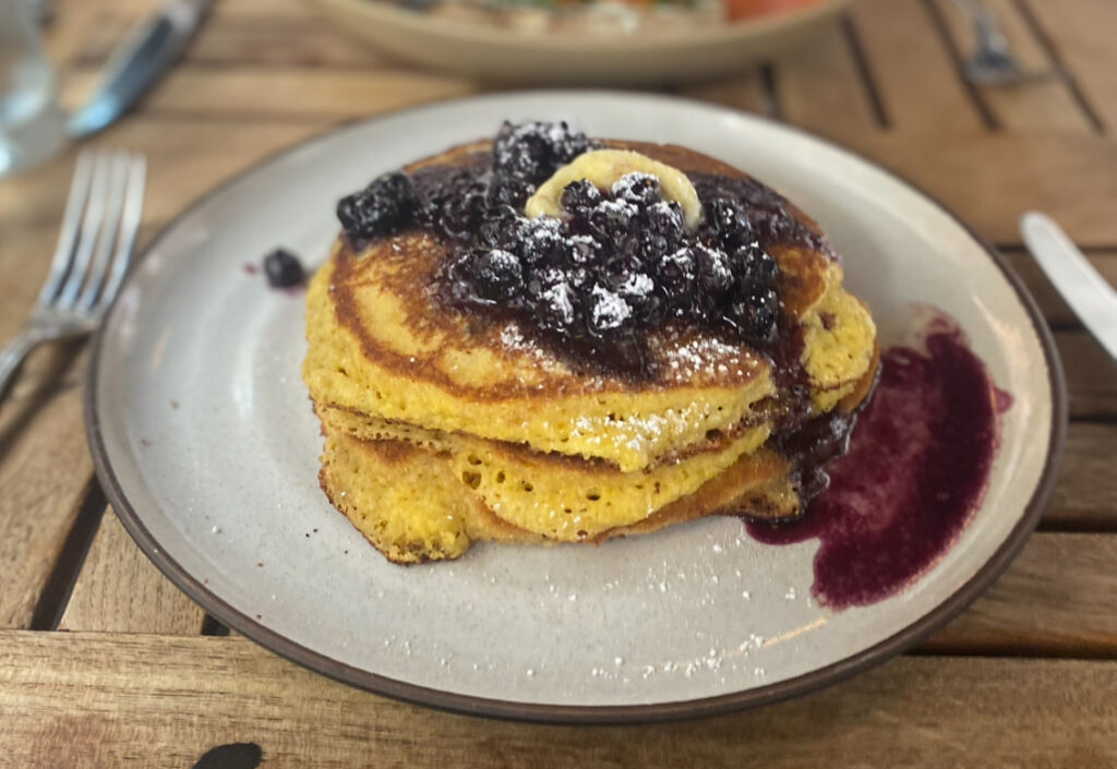 a stack of cornmeal pancakes with berry compote on a plate.