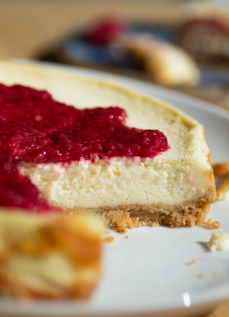 A close up on the interior of a cottage cheese cheesecake topped with a raspberry compote.