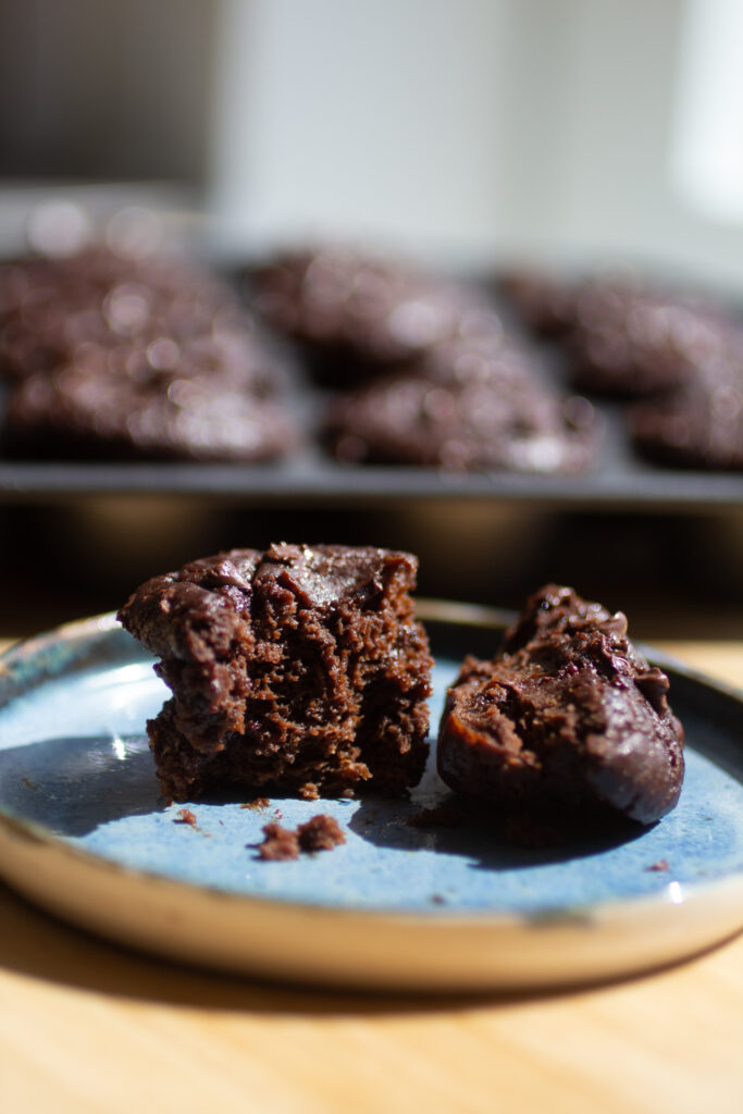 A mini chocolate chip muffin broken in half and placed on a blue plate.
