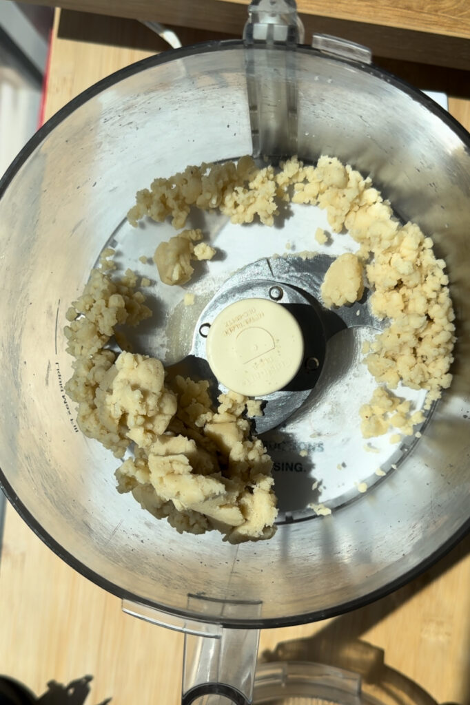 Bits of crumbly almond paste in a food processor.
