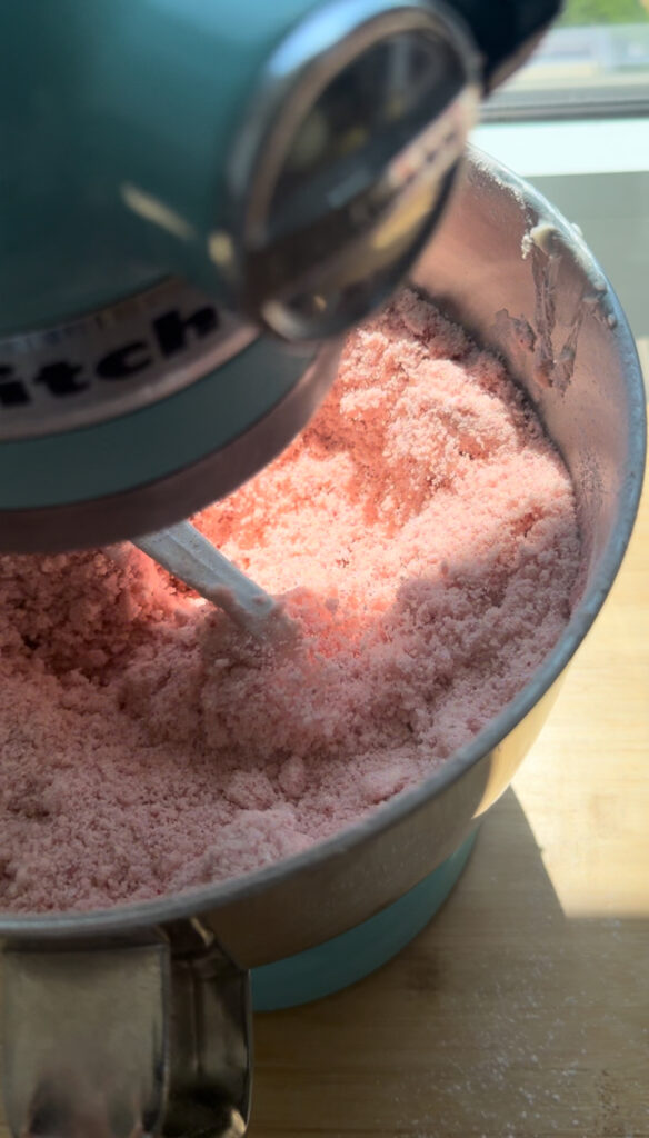 A mixing bowl with a crumbly mixture of strawberry cake batter.
