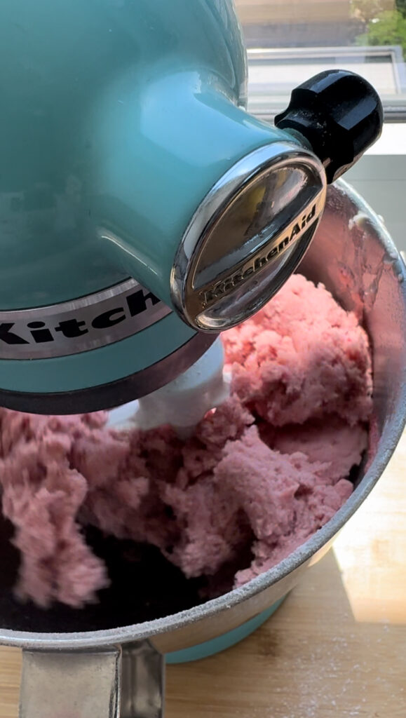 A mixing bowl with a stiff mixture of strawberry cake batter.
