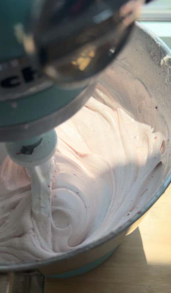 A mixing bowl with a lightened mixture of strawberry cake batter after mixing for additional time.