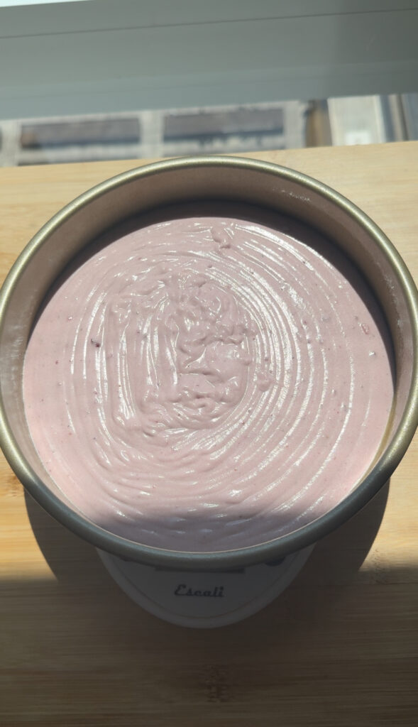 A round baking pan filled with strawberry cake batter.