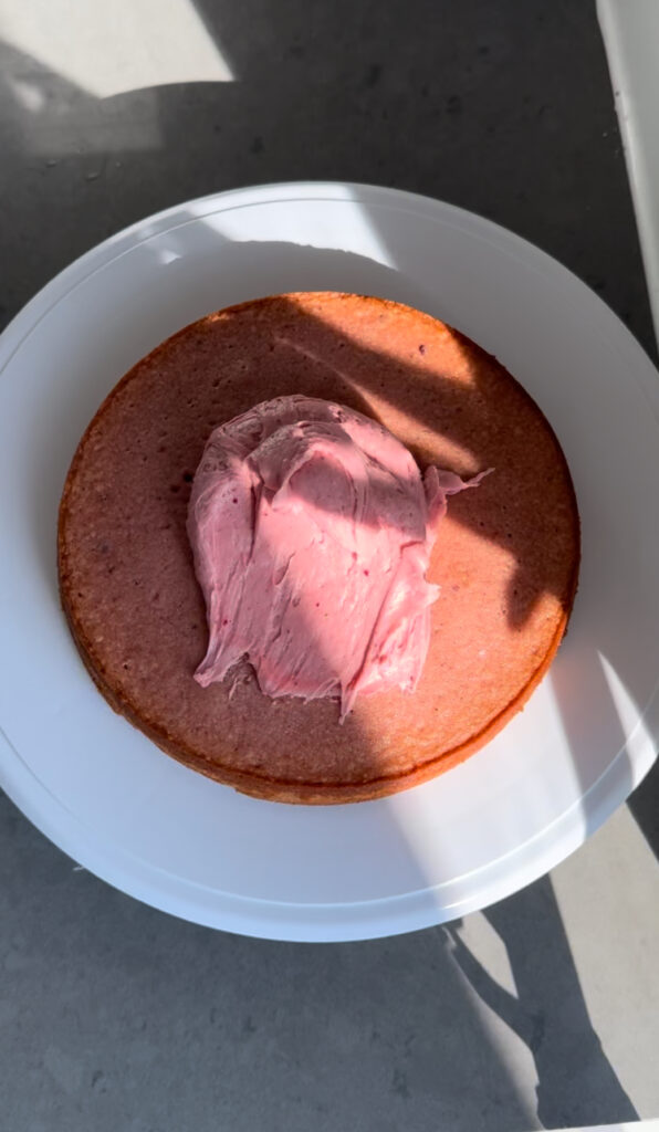 A layer of strawberry cake with a dollop of frosting on top.