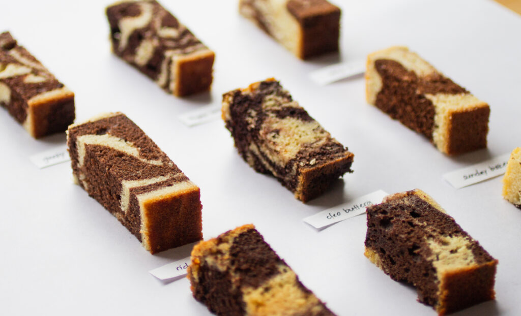 horizontal image of 9 slices of marble cake on a gray background.