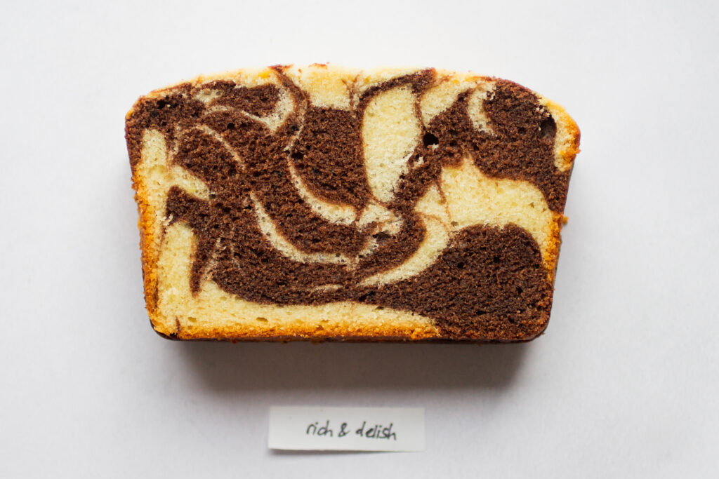 a slice of rich and delish marble cake on a white background.