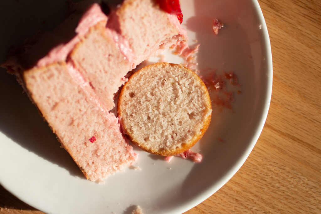 strawberry cake with food coloring next to a lighter color round of cake with no food coloring.