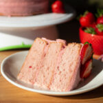 a slice of triple layer strawberry cake on a white plate.