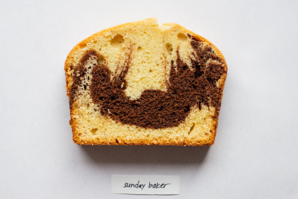 a slice of sunday baker marble cake on a white background.