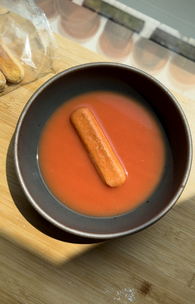 a ladyfinger soaking in blood orange juice.
