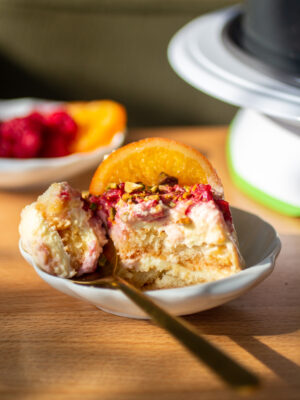 A slice of blood orange raspberry tiramisu on a plate with a fork.