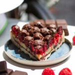 a slice of chocolate raspberry tart on a blue plate.