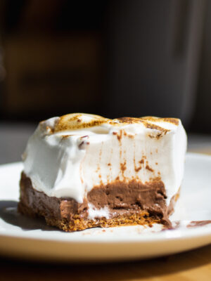 a half eaten slice of chocolate s'mores pie on a white plate.