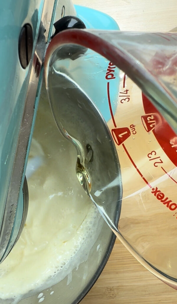 Pouring oil into a whipped egg mixture.
