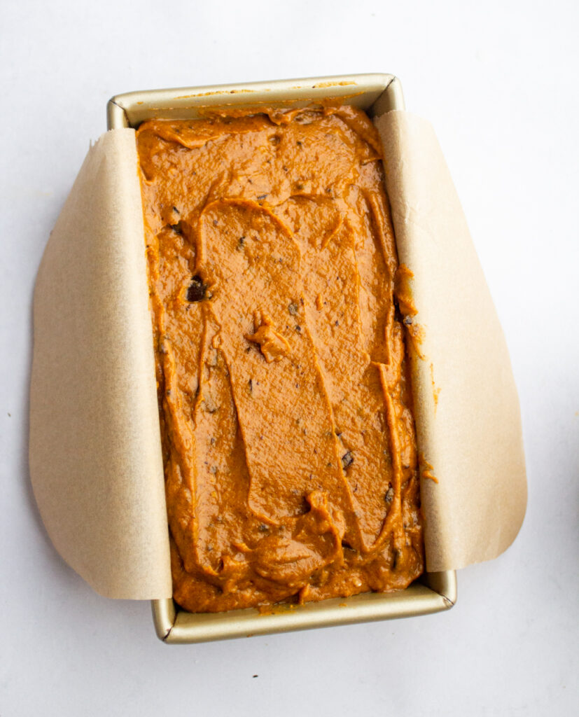 pumpkin bread batter in a parchment-lined loaf pan.