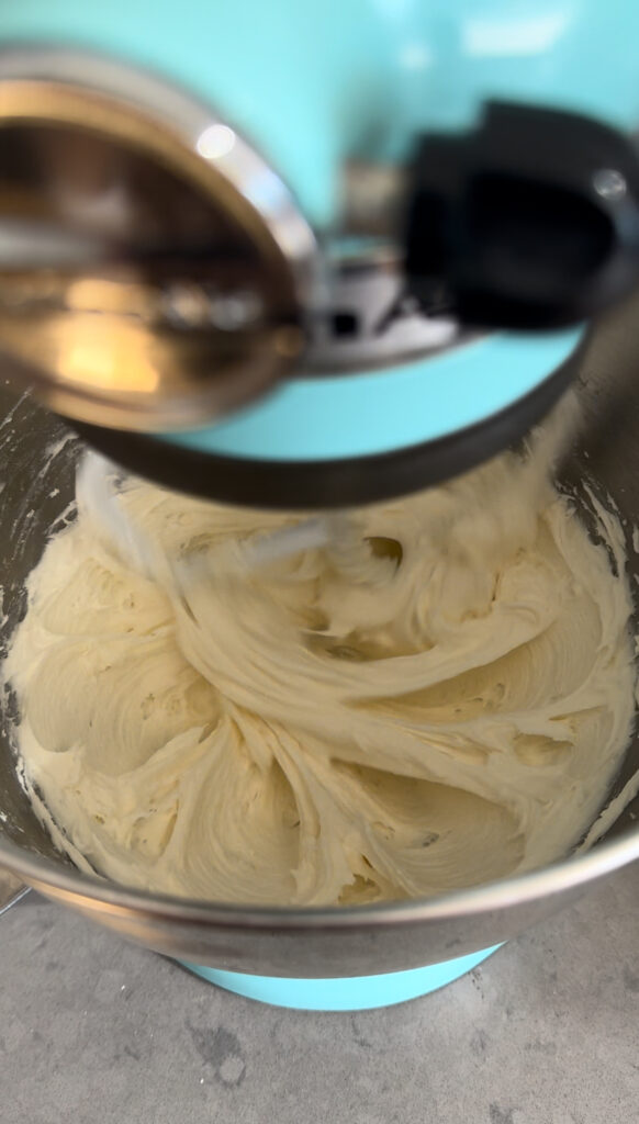 Cream cheese frosting being beaten a KitchenAid mixer.