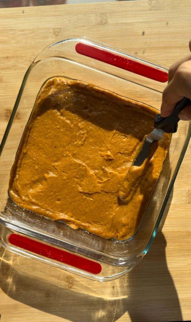 Spreading the pumpkin cake batter into an 8x8 pan.