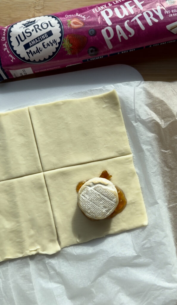 A round of brie on top of jam on a puff pastry square.