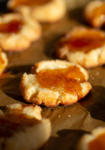 A cheesy jam thumbprint cookie on a cookie sheet.