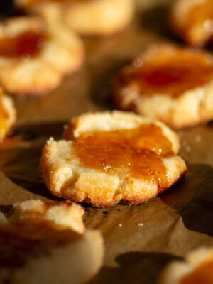 A cheesy jam thumbprint cookie on a cookie sheet.