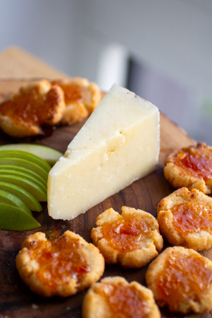 A wedge of Pecorino Romano surrounded by thumbprint cookies.