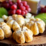 pumpkin-shaped brie bites on a cheeseboard.