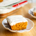 A slice of pumpkin sheet cake on a white plate.