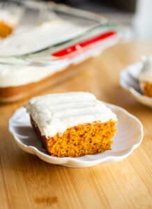 A slice of pumpkin sheet cake on a white plate.