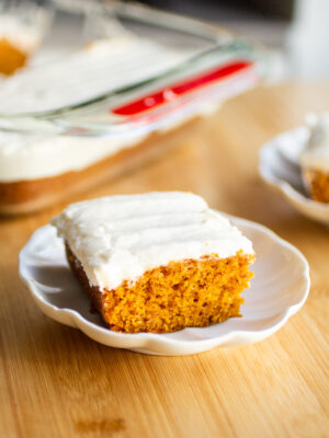 A slice of pumpkin sheet cake on a white plate.