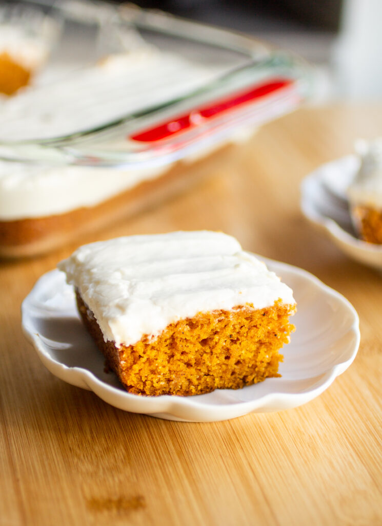 A slice of pumpkin sheet cake on a white plate.