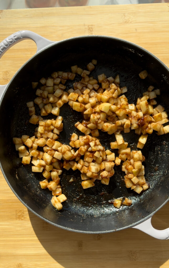 Cooked, spiced apple cubes in a pan.