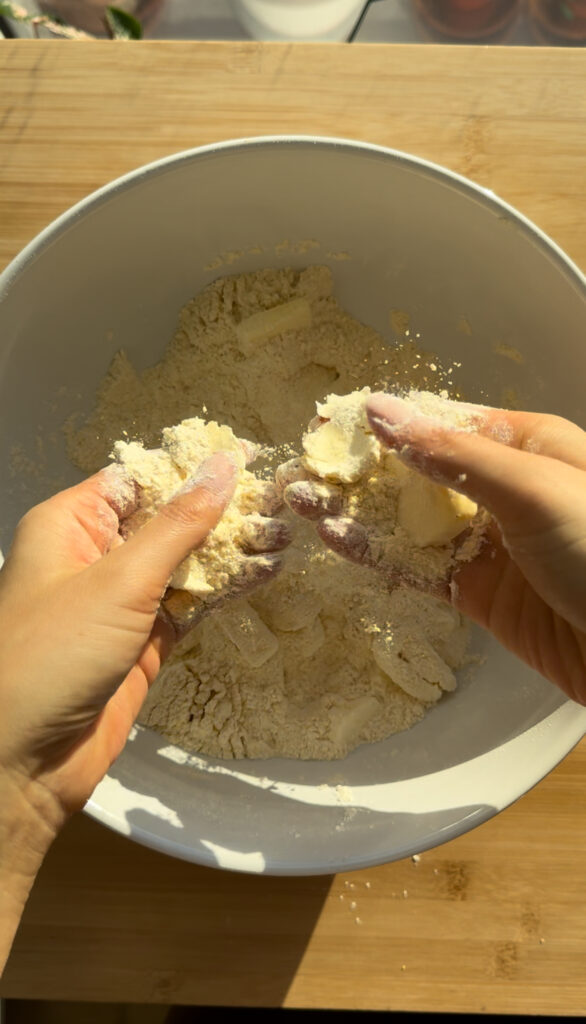 Hands rubbing butter into flour.
